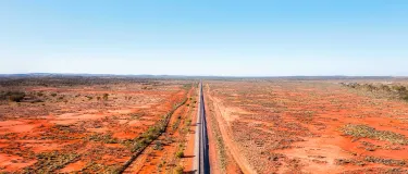 Railway track in red soil Australian outback leading to Broken hill silver city of far west - aerial panorama. istock-1367592083-16x9-adj.jpg