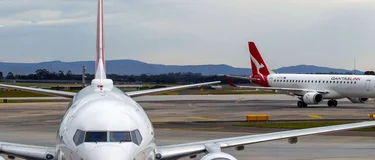 Aircraft on the tarmac at Melbourne Airport, with a QantasLink jet taxiing in the background.