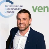 Portrait of Evan Smith, Sustainability Manager at Holcim, smiling in front of an Infrastructure Sustainability Council event backdrop.