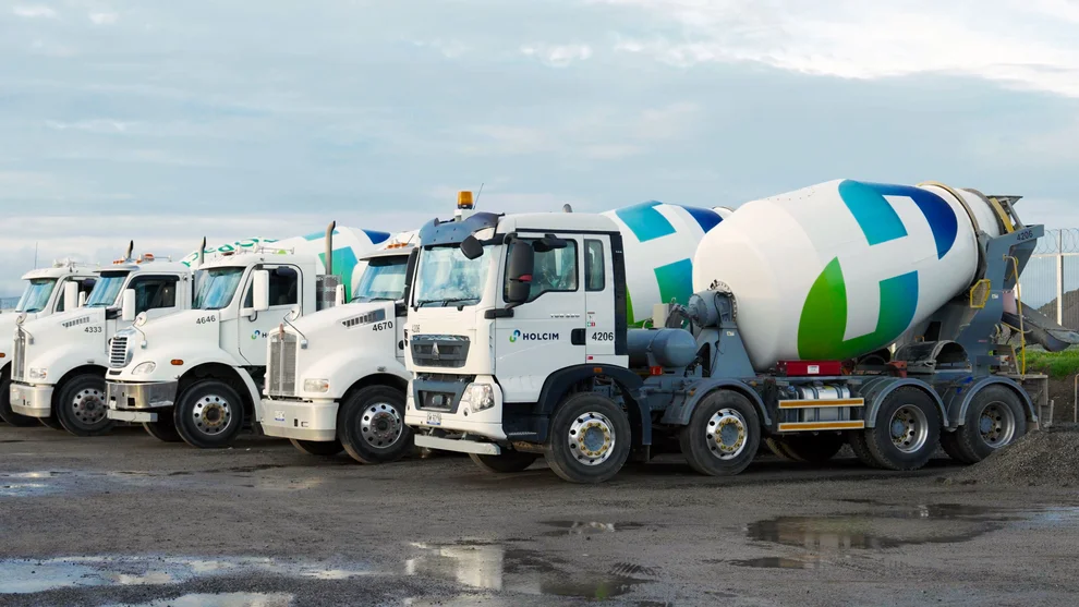 A row of Holcim concrete agitator mixer trucks parked on site at Melbourne Airport.