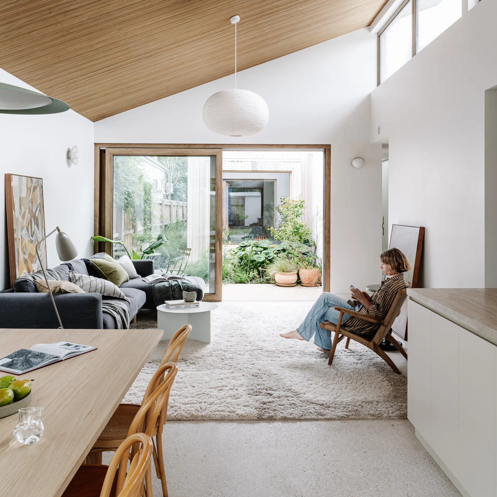 Raked timber-lined ceiling and clerestory windows above the living area, looking through to the garden.